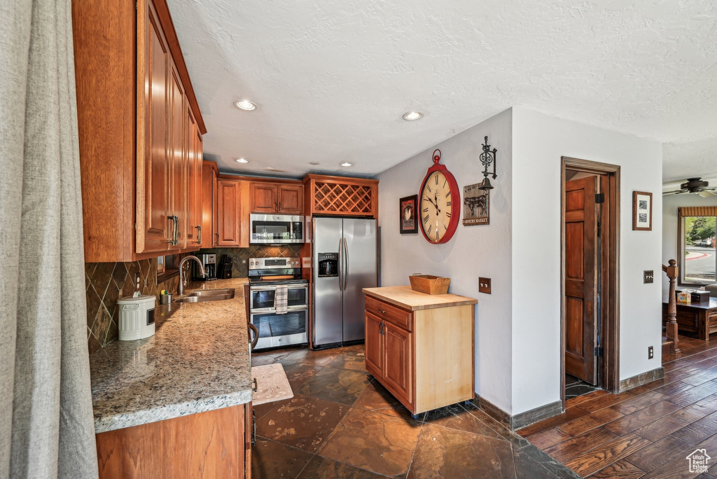 Kitchen featuring appliances with stainless steel finishes, a sink, decorative backsplash, baseboards, and recessed lighting