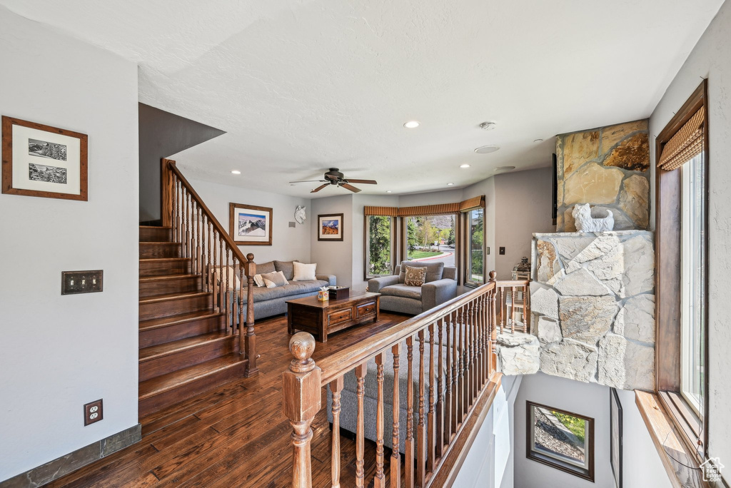 Living room with wood finished floors, a ceiling fan, recessed lighting, and stairway