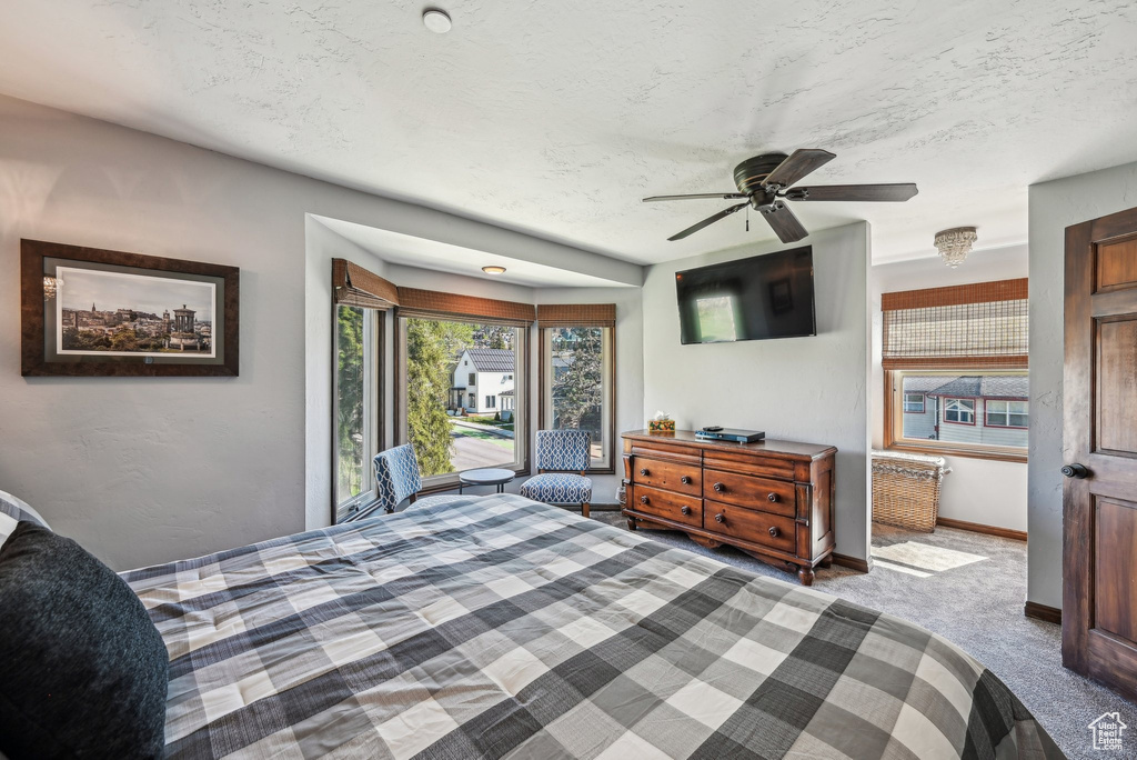 Carpeted bedroom with baseboards, a textured ceiling, and ceiling fan