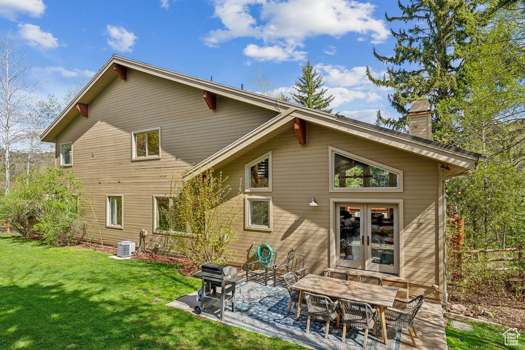 Back of property with a chimney, french doors, a patio, a yard, and cooling unit