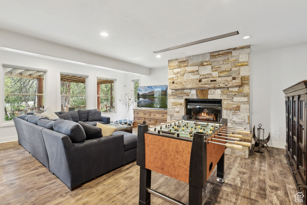 Living room with wood finished floors, a stone fireplace, recessed lighting, and baseboards
