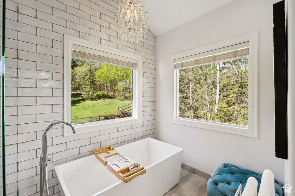 Full bathroom featuring a freestanding bath, lofted ceiling, a chandelier, tile patterned flooring, and baseboards