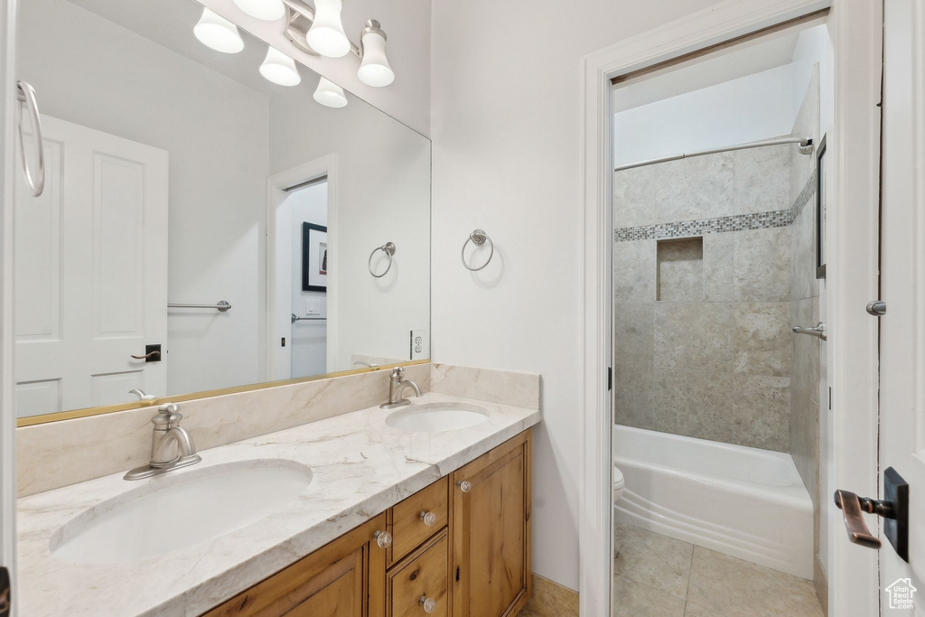 Bathroom featuring double vanity, tile patterned floors, toilet, and shower / bath combination