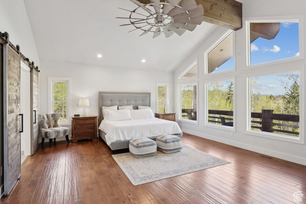 Bedroom featuring a barn door, high vaulted ceiling, dark wood-type flooring, recessed lighting, and baseboards