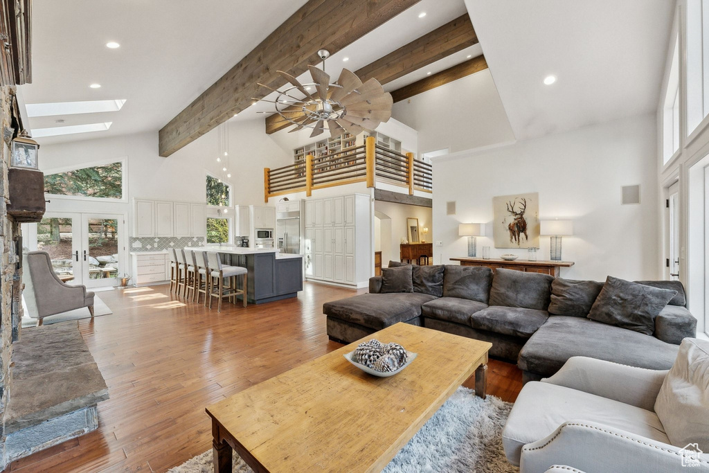 Living area featuring high vaulted ceiling, a skylight, beam ceiling, a ceiling fan, and recessed lighting