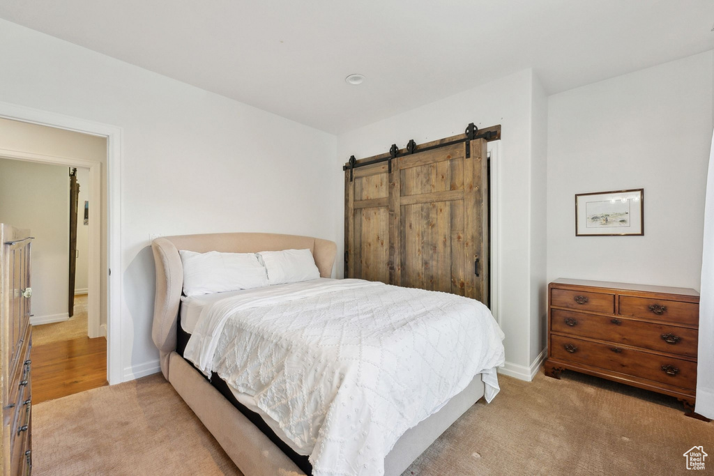 Bedroom with light colored carpet, baseboards, and a barn door