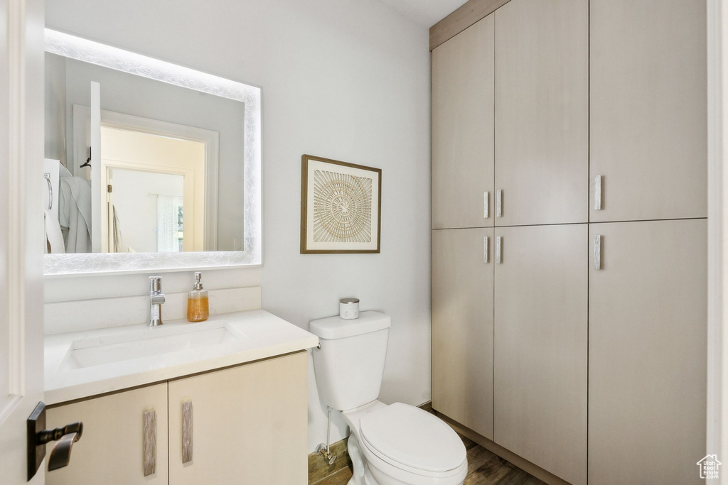 Bathroom featuring vanity, toilet, and wood finished floors