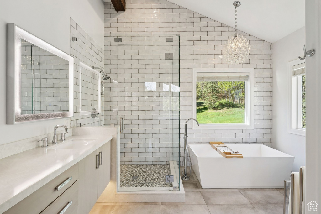 Full bathroom featuring a stall shower, vaulted ceiling, vanity, a soaking tub, and tile patterned floors