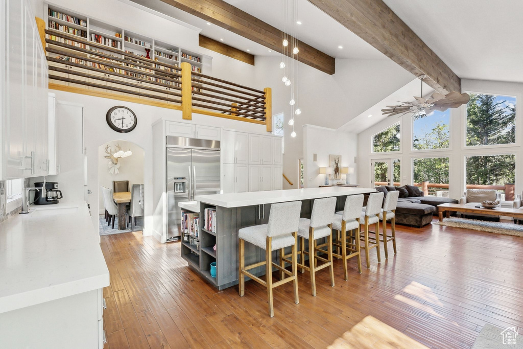 Kitchen with stainless steel built in fridge, high vaulted ceiling, open floor plan, white cabinets, and beam ceiling
