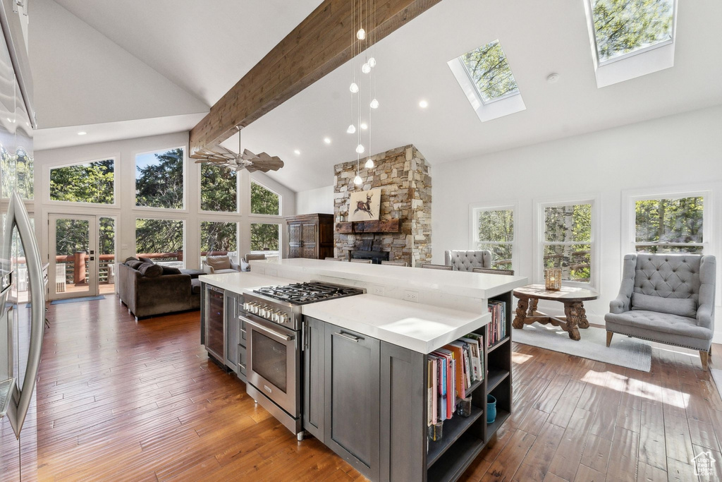 Kitchen with open floor plan, high vaulted ceiling, stainless steel appliances, a fireplace, and beam ceiling
