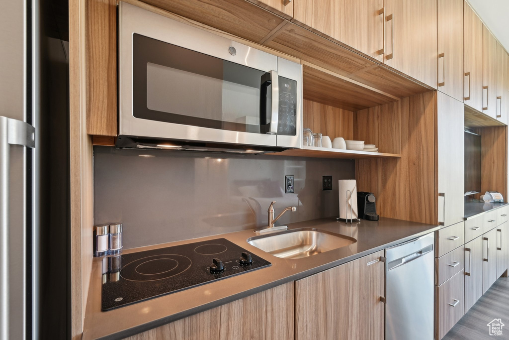 Kitchen with appliances with stainless steel finishes, modern cabinets, a sink, and light brown cabinetry