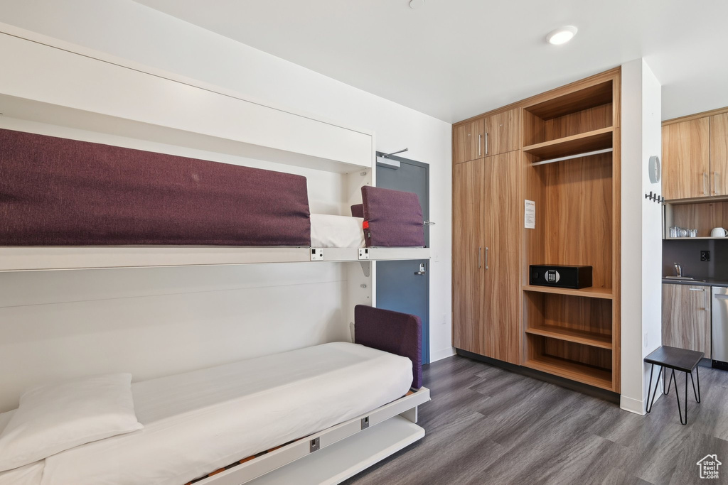 Bedroom featuring dark wood-style flooring, a sink, and baseboards