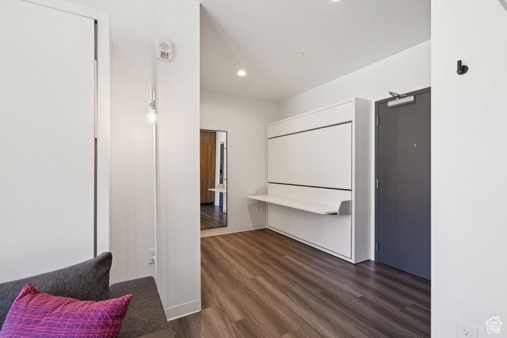 Hallway with dark wood finished floors, recessed lighting, and baseboards