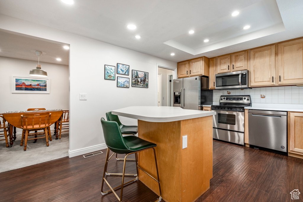 Kitchen featuring appliances with stainless steel finishes, recessed lighting, dark wood-style floors, light countertops, and a kitchen island