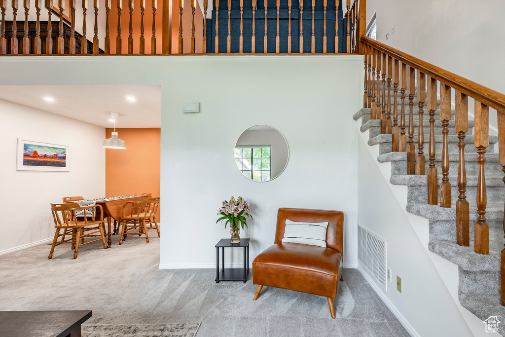 Living area with a towering ceiling, carpet floors, stairway, and baseboards