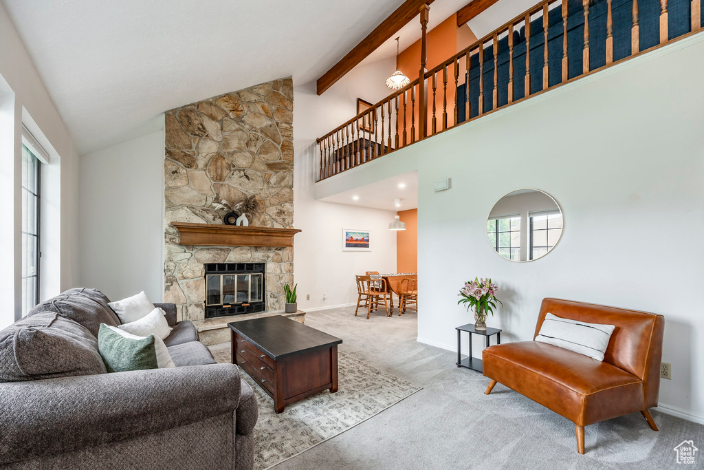 Living room with carpet, plenty of natural light, high vaulted ceiling, a fireplace, and beam ceiling