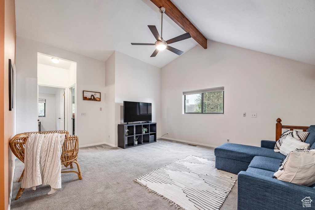 Living area featuring healthy amount of natural light, ceiling fan, beamed ceiling, light carpet, and baseboards