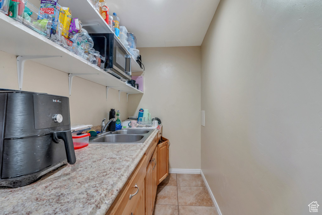 Washroom with a sink, light tile patterned floors, and baseboards