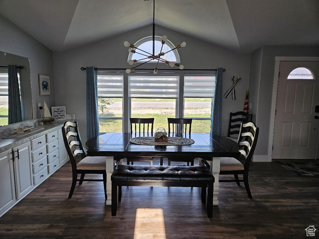 Dining space with vaulted ceiling, a chandelier, plenty of natural light, dark wood-style floors, and baseboards