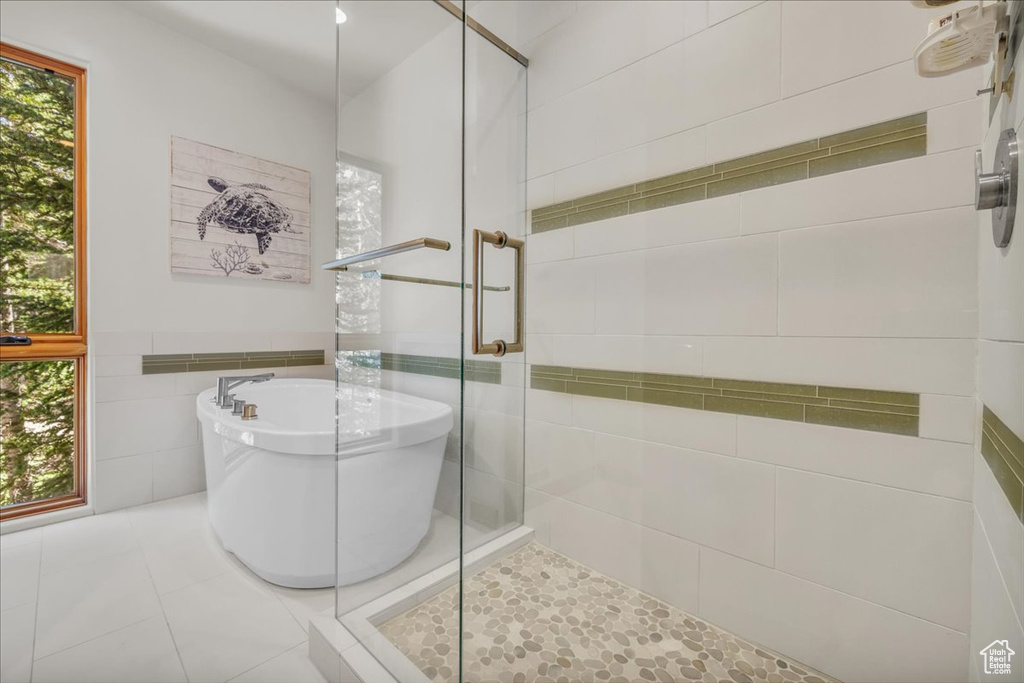 Full bath with a stall shower, a freestanding bath, tile walls, and tile patterned floors