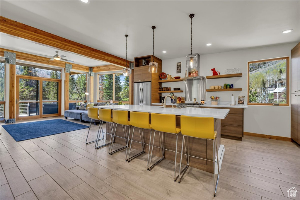 Kitchen featuring open shelves, freestanding refrigerator, light countertops, a kitchen breakfast bar, and baseboards