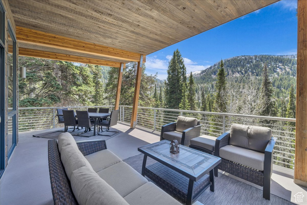 View of patio / terrace featuring an outdoor hangout area, a forest view, outdoor dining space, and a mountain view