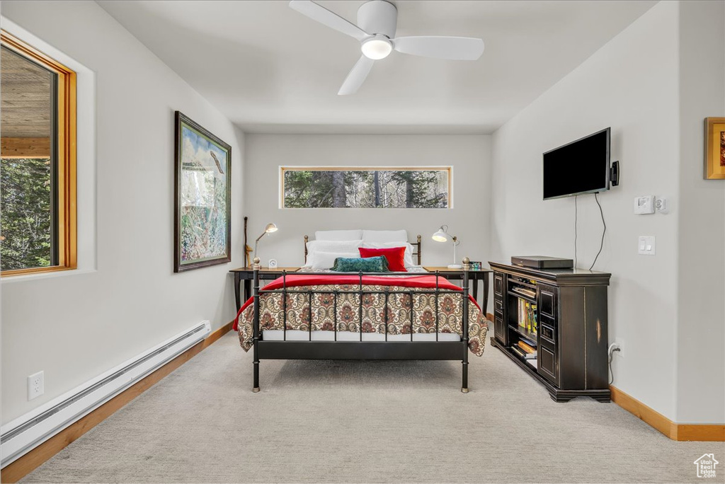 Carpeted bedroom featuring a baseboard heating unit, baseboards, and a ceiling fan