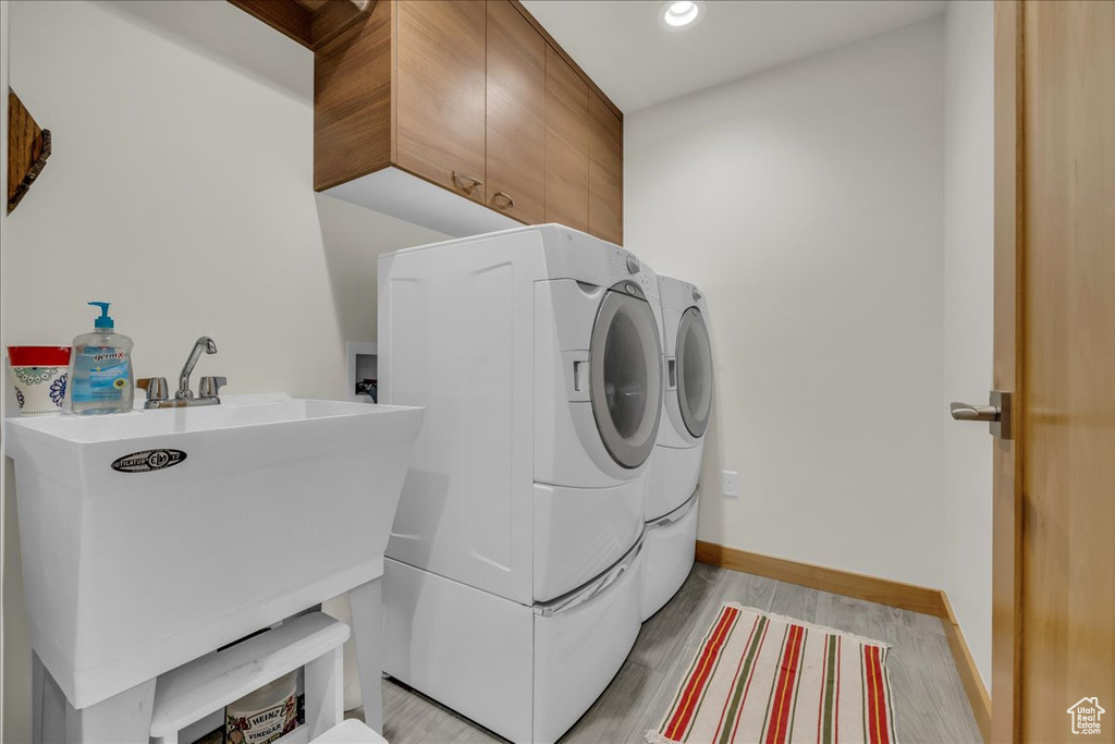 Washroom featuring cabinet space, washer and dryer, baseboards, recessed lighting, and light wood finished floors