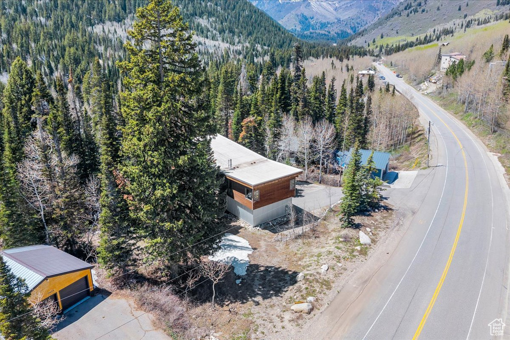 View of subject property featuring a mountain backdrop and a forest