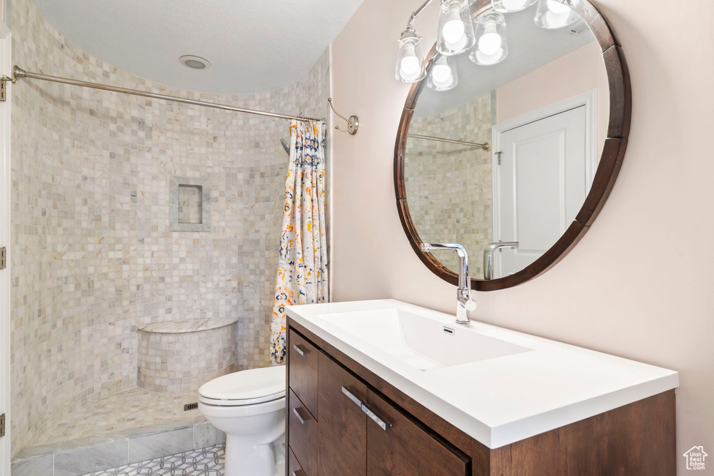 Full bath with a tile shower, toilet, vanity, and tile patterned floors