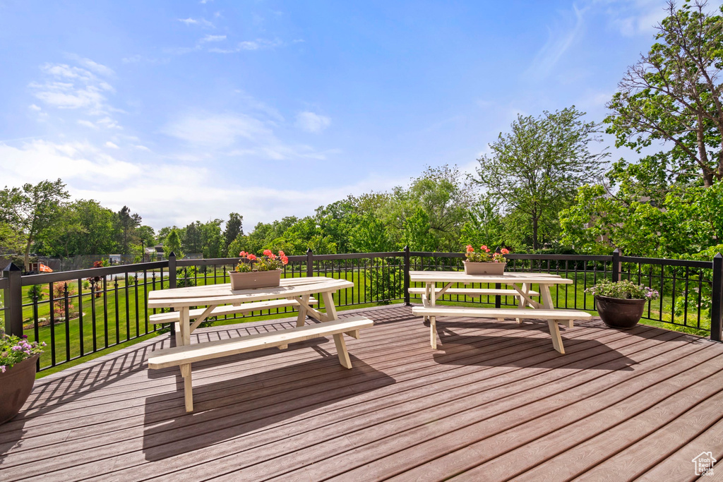 Deck featuring a lawn, outdoor dining area, and view of scattered trees