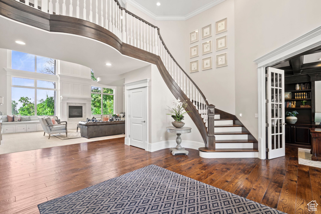 Entrance foyer featuring a high ceiling, hardwood / wood-style flooring, stairs, ornamental molding, and baseboards