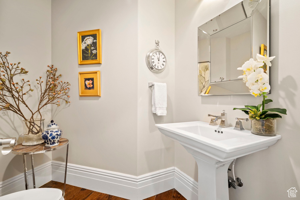 Half bath with baseboards, wood finished floors, and a sink