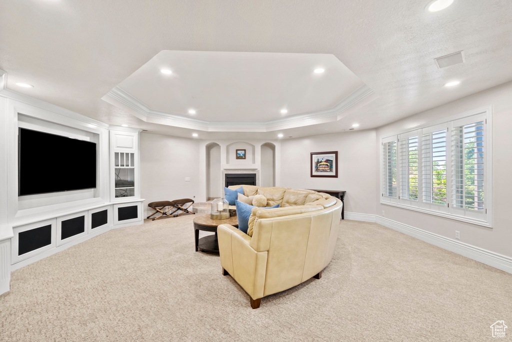 Living room with light colored carpet, recessed lighting, arched walkways, a tray ceiling, and crown molding