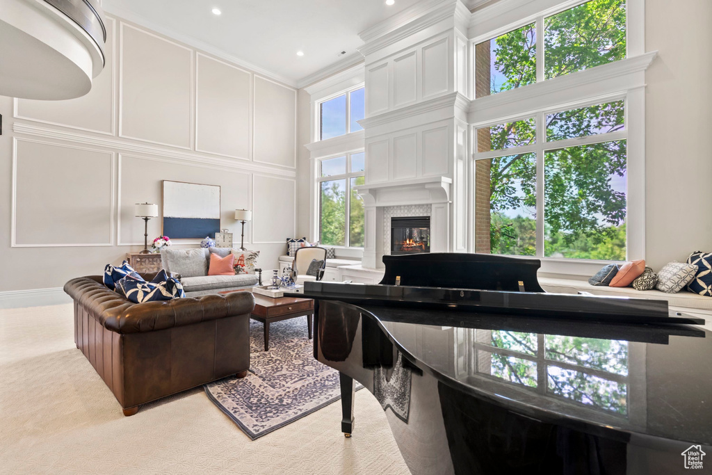 Living room featuring a high ceiling, a fireplace, a decorative wall, ornamental molding, and recessed lighting