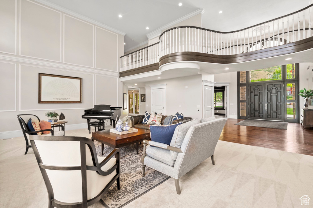 Living room featuring light colored carpet, ornamental molding, a towering ceiling, recessed lighting, and baseboards