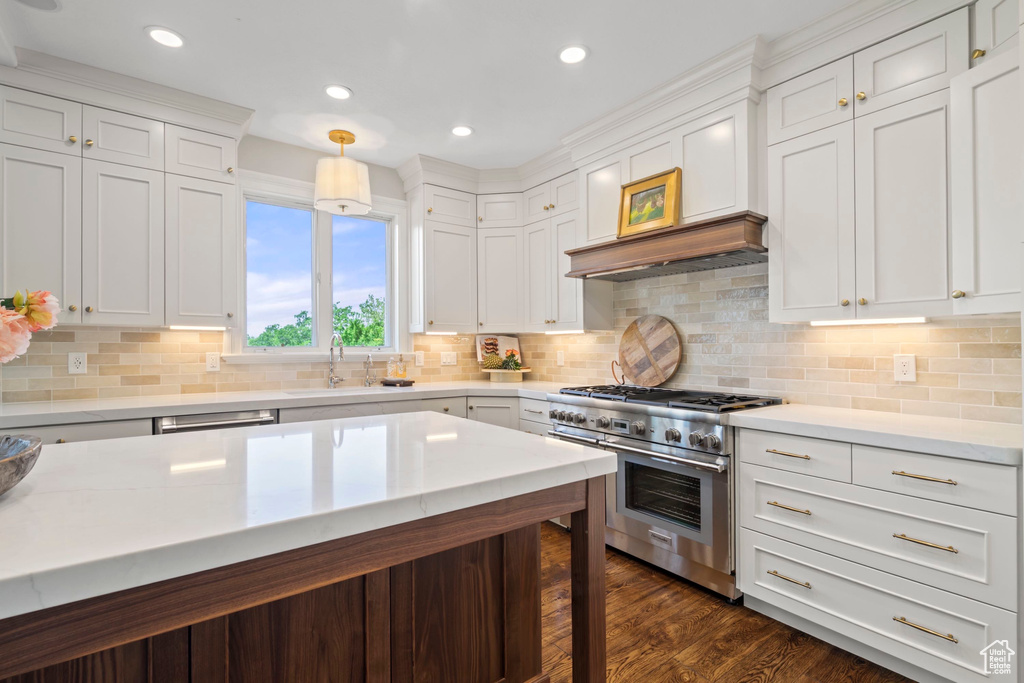 Kitchen with range with two ovens, light countertops, a sink, white cabinets, and recessed lighting