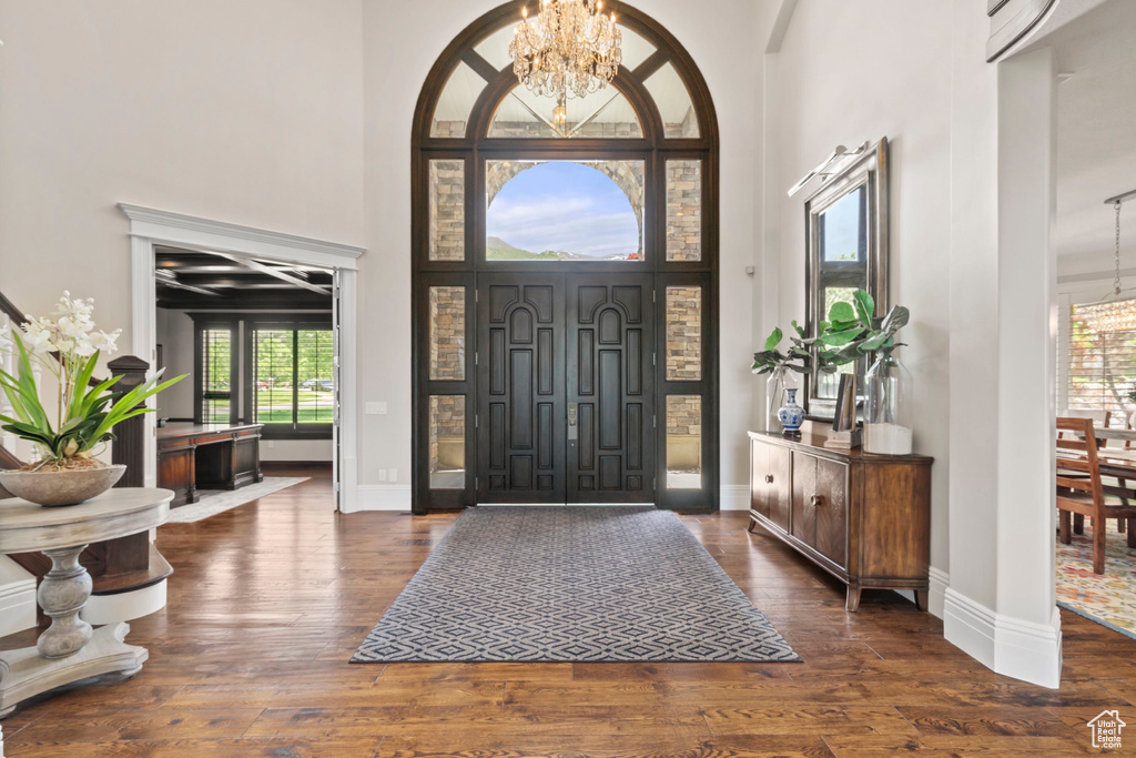 Foyer entrance featuring a chandelier, a towering ceiling, hardwood / wood-style floors, and baseboards