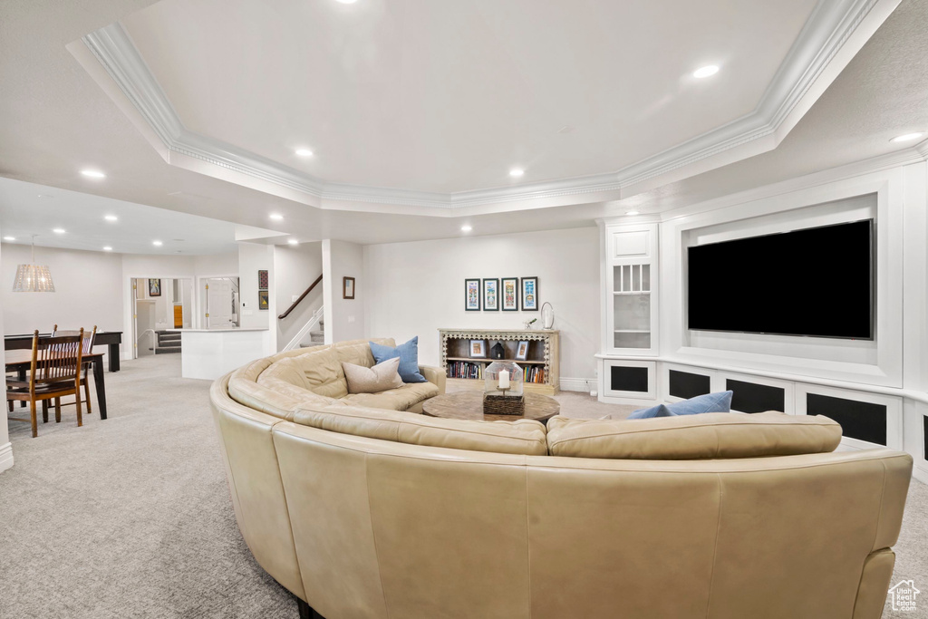 Living room featuring light colored carpet, ornamental molding, a tray ceiling, recessed lighting, and stairs