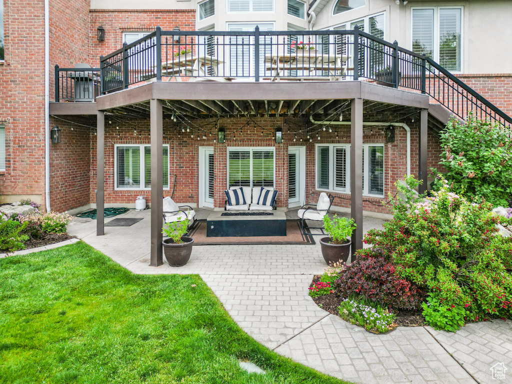 Back of house with brick siding, outdoor lounge area, a patio, and a wooden deck