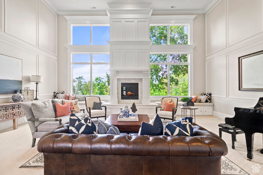 Living area featuring a decorative wall, a towering ceiling, a glass covered fireplace, and crown molding