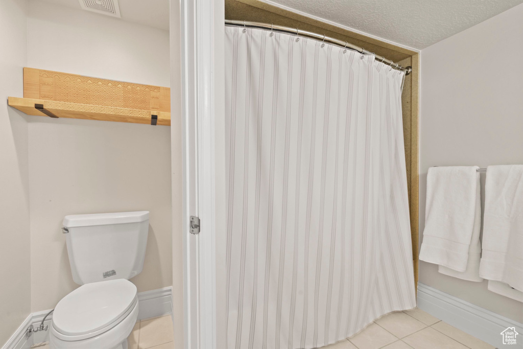 Bathroom featuring tile patterned flooring, toilet, and a shower with curtain