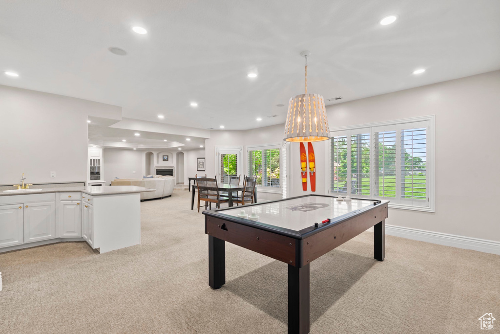 Recreation room featuring light carpet, a sink, recessed lighting, and baseboards