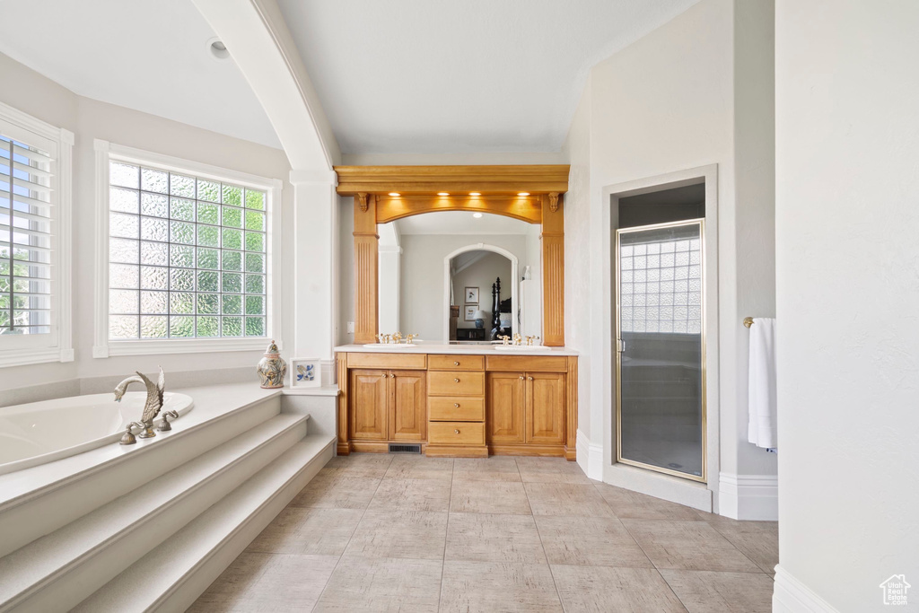 Full bathroom featuring double vanity, a stall shower, a garden tub, and baseboards