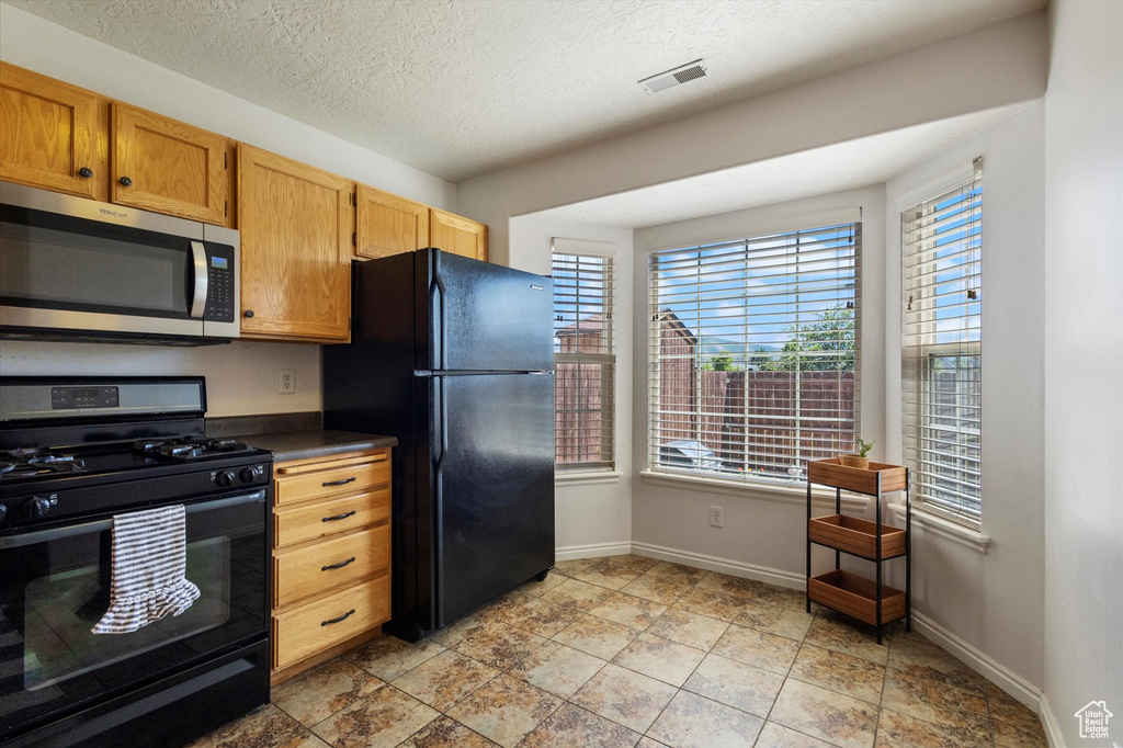 Kitchen with black appliances, healthy amount of natural light, dark countertops, and a textured ceiling