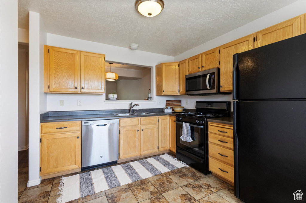 Kitchen with black appliances, dark countertops, and a textured ceiling