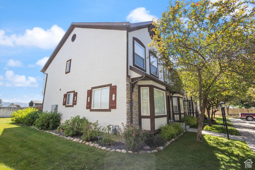 View of side of property featuring stone siding, stucco siding, and a yard