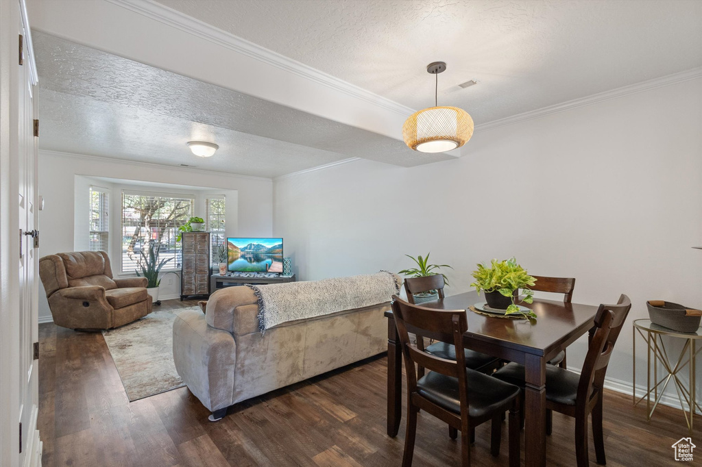Dining room featuring dark wood-style flooring, ornamental molding, and a textured ceiling