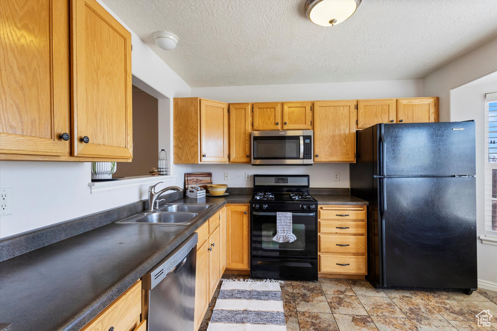 Kitchen with black appliances, dark countertops, and a textured ceiling
