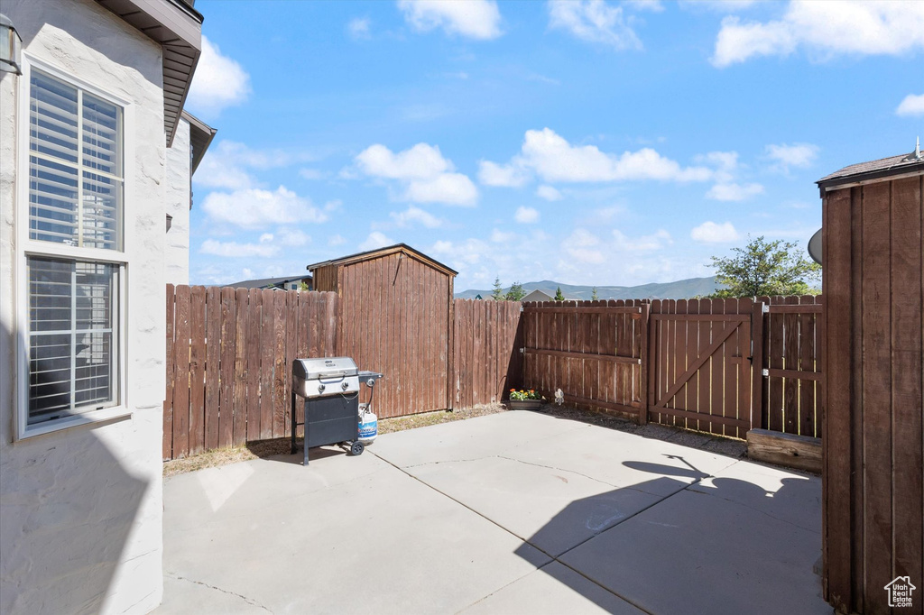 Fenced backyard featuring a grill, a patio, a gate, and a mountain view